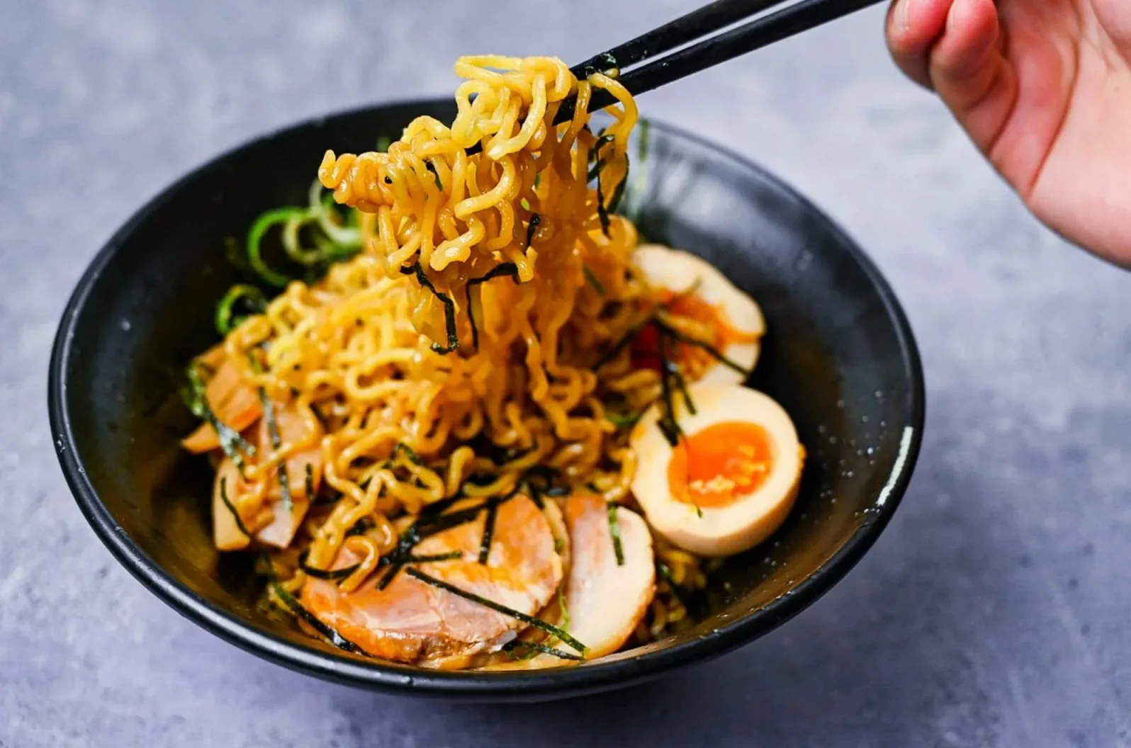 黄色い縮れ麺と半熟卵、チャーシューのラーメン
